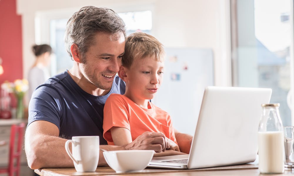 A father an son using a laptop at home